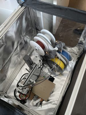 The new aluminium frame being fitted inside the enclosure, alongside the printer and filament spools
